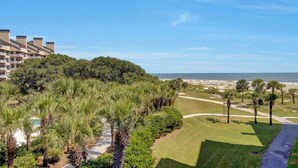 A resort with a golf course, beachfront, and a building with multiple balconies.