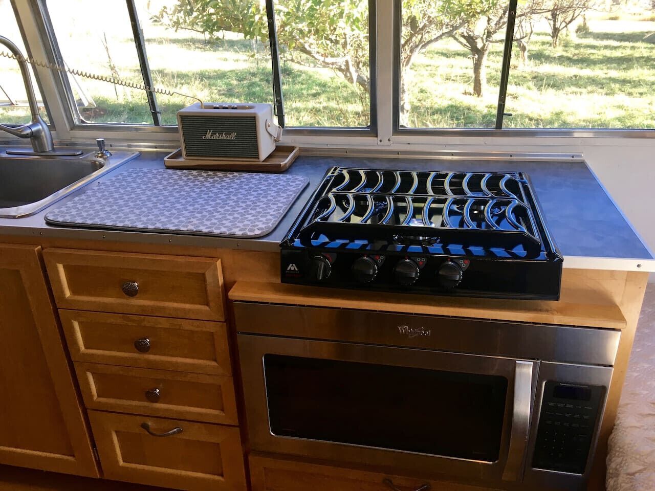 Cucina con piano cottura integrato, forno e finestra vista alberi.