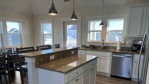 Eine moderne Küche mit Granit-Arbeitsplatten, weißen Schränken und Edelstahlgeräten.