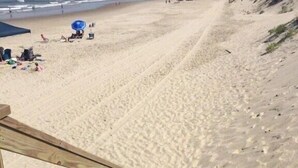 Eine Holztreppe führt zu einem Sandstrand mit freiem Blick auf den Ozean.