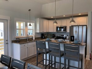 A modern kitchen with white cabinets, stainless steel appliances, and a central island with bar stools.