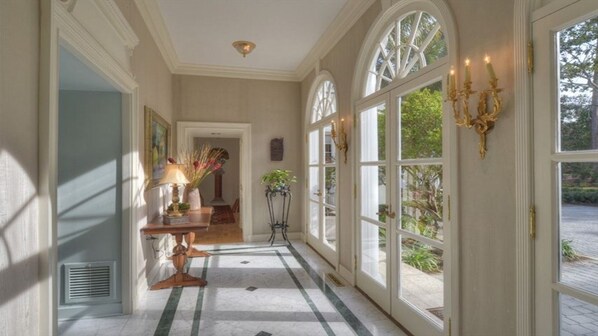 Classic corridor with arched windows, checkered floor, and elegant artwork.