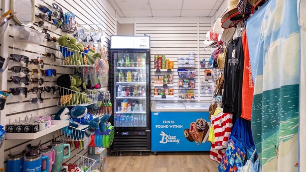 A store with shelves of sunglasses, a refrigerator stocked with beverages, and a blue banner advertising Blue Bunny ice cream. - DISCOUNTED RATES!   BREATHTAKING VIEWS FROM BEAUTIFUL CORNER UNIT!  3 BR/2 BA. (Orange Beach)