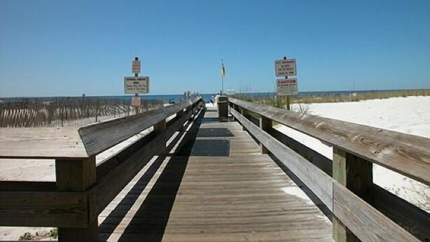 A wooden boardwalk leading to a beach with signs indicating a lifeguard on duty and a warning about strong currents. - DISCOUNTED RATES!   BREATHTAKING VIEWS FROM BEAUTIFUL CORNER UNIT!  3 BR/2 BA. (Orange Beach)