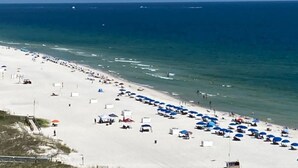 A beach with rows of umbrellas and beach chairs, a sandy shore, and the ocean in the background. - DISCOUNTED RATES!   BREATHTAKING VIEWS FROM BEAUTIFUL CORNER UNIT!  3 BR/2 BA. (Orange Beach)