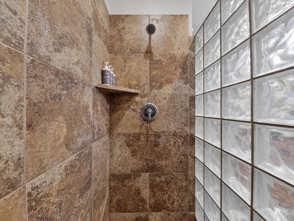 A shower area with brown tiles and a glass shower enclosure.
