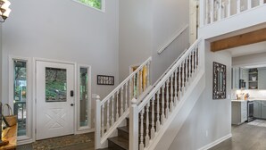 Un interior espacioso con una escalera, una puerta con paneles de vidrio y una zona de cocina.