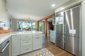 A modern kitchen with a large island, stainless steel appliances, and a view of the outdoors.