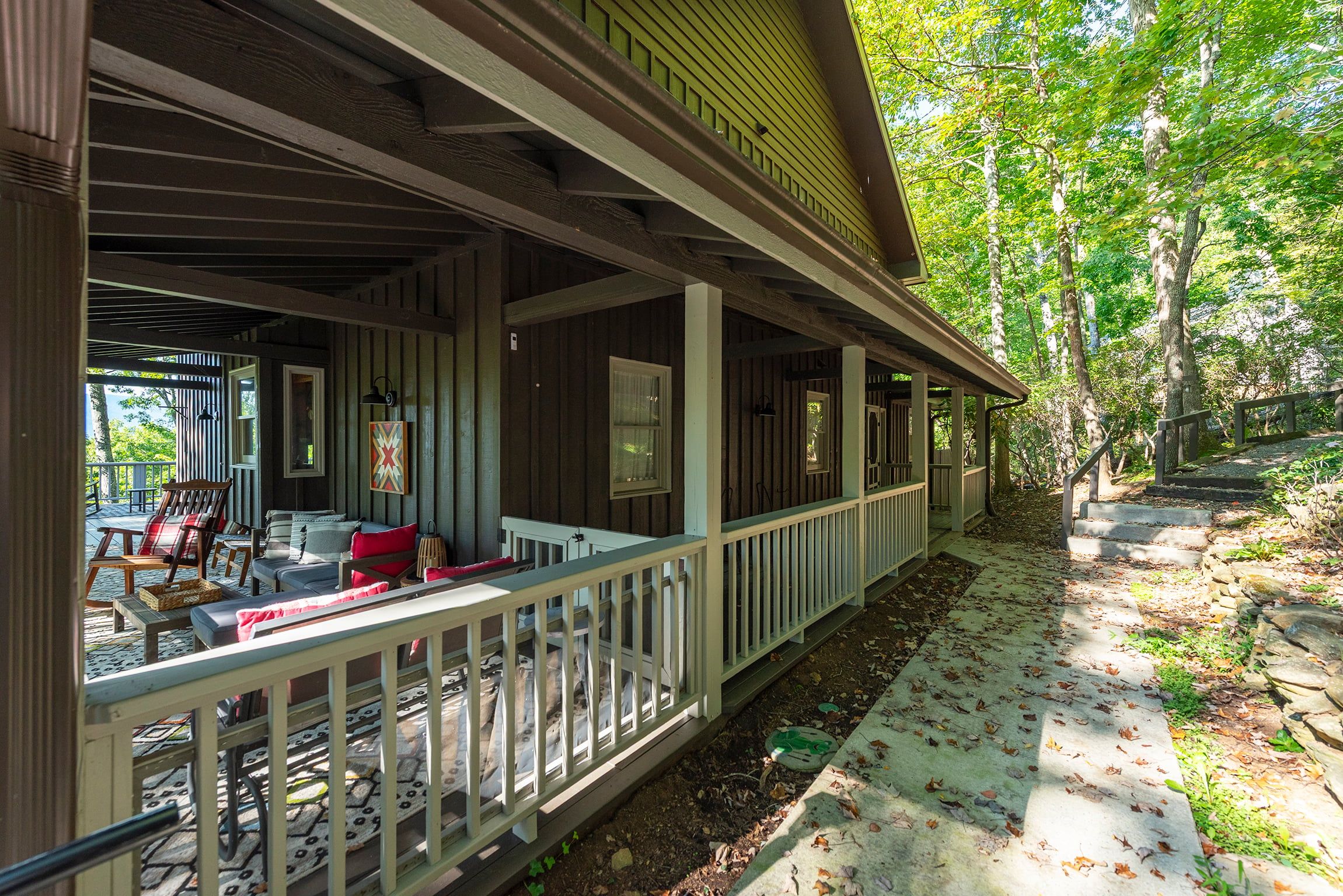 A covered porch with outdoor seating, a wooden deck, and a stone pathway.