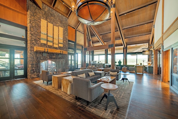 A spacious interior with a stone wall, wooden ceiling beams, and a fireplace. - Exceptional Home Near SR Village / Hot Tub / SHARC Passes / AC / Wi Fi / Bikes (Sunriver)