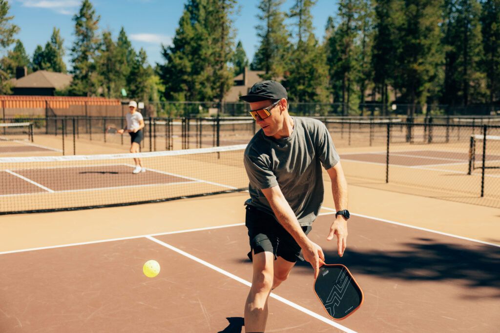 En tennisbane med net, en tennisbold i spil, og to spillere.