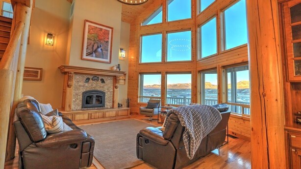 A spacious living room with a fireplace, leather recliners, and large windows offering a view of the landscape.
