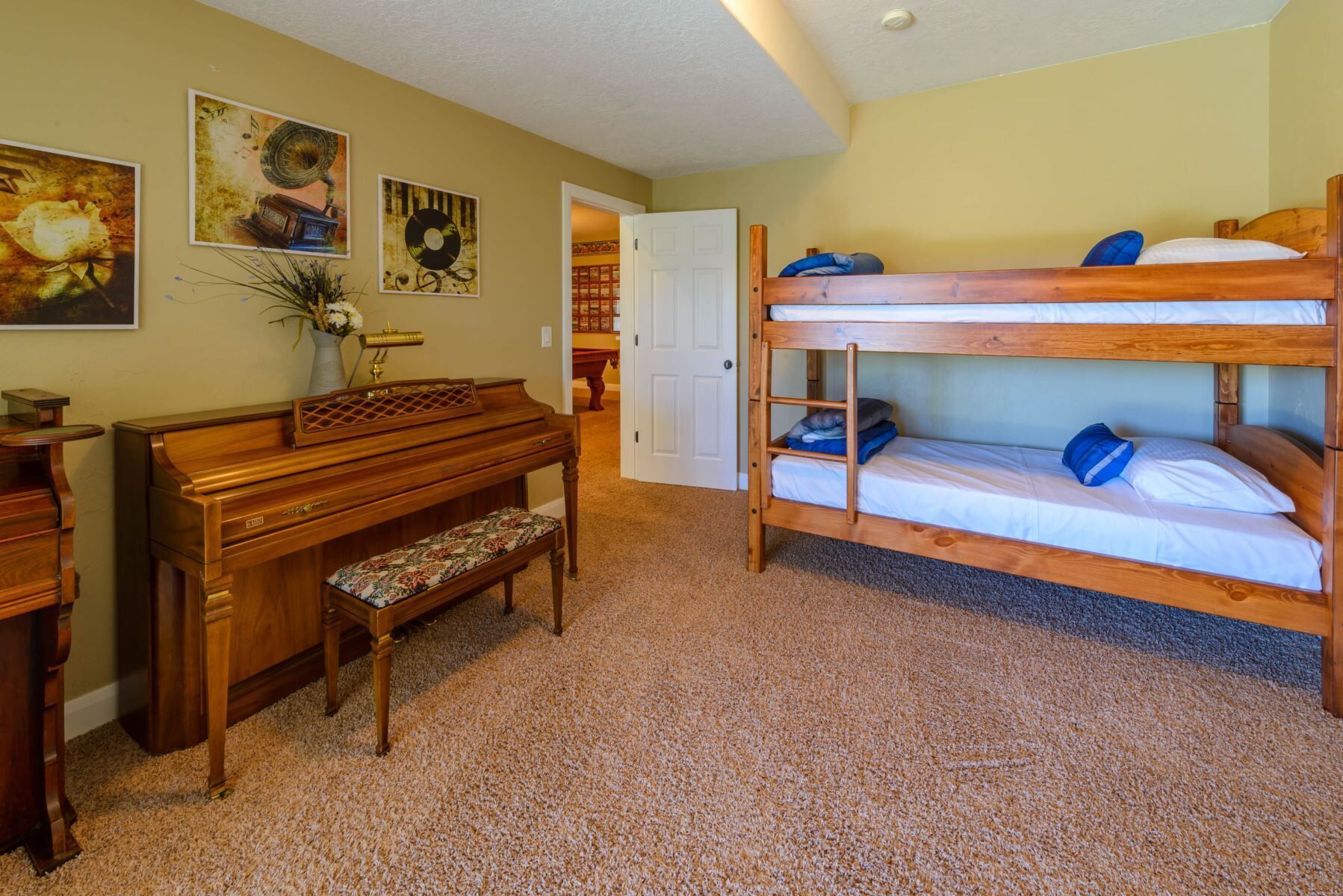 A room with a bunk bed, a wooden desk with a piano, and a bench.