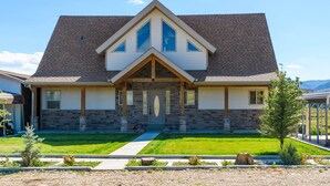 A two-story house with a gabled roof, stone foundation, and a front porch with a door.