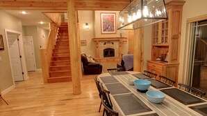 A spacious dining area with a long table, wooden chairs, and a fireplace.