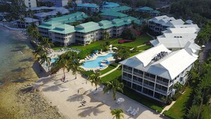 An aerial view of a resort with multiple buildings, a beach, and a pool area.
