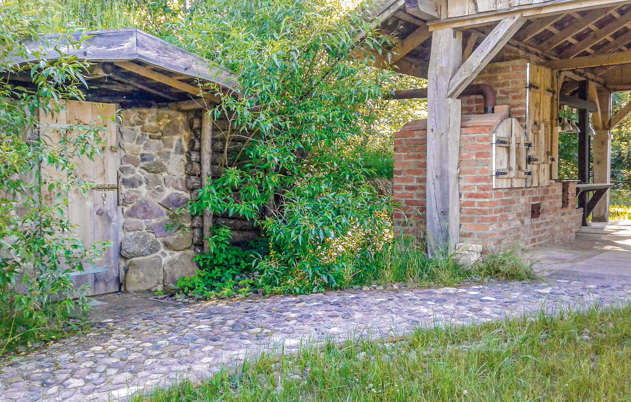 Un bâtiment rustique en pierre avec un toit en bois, une structure en briques dotée d’une fenêtre et un chemin pavé de pierres.