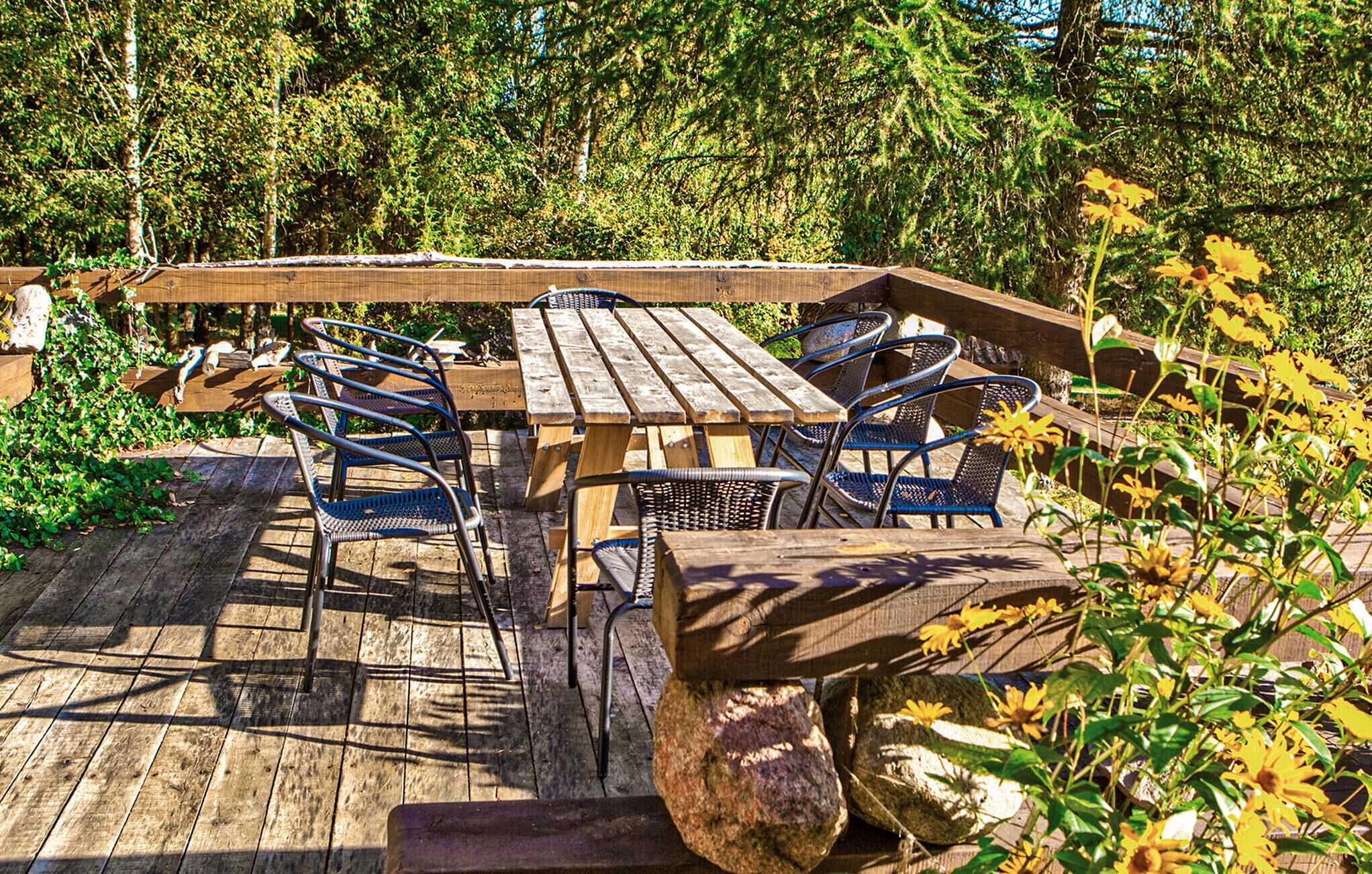Une terrasse extérieure en bois, avec une table de pique-nique et des chaises en métal.