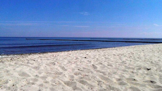A beach with a clear sky, sandy shore, and a long pier extending into the water. - Hus at Zickenbarg - Apartment Hus at Zickenbarg (Zempin)