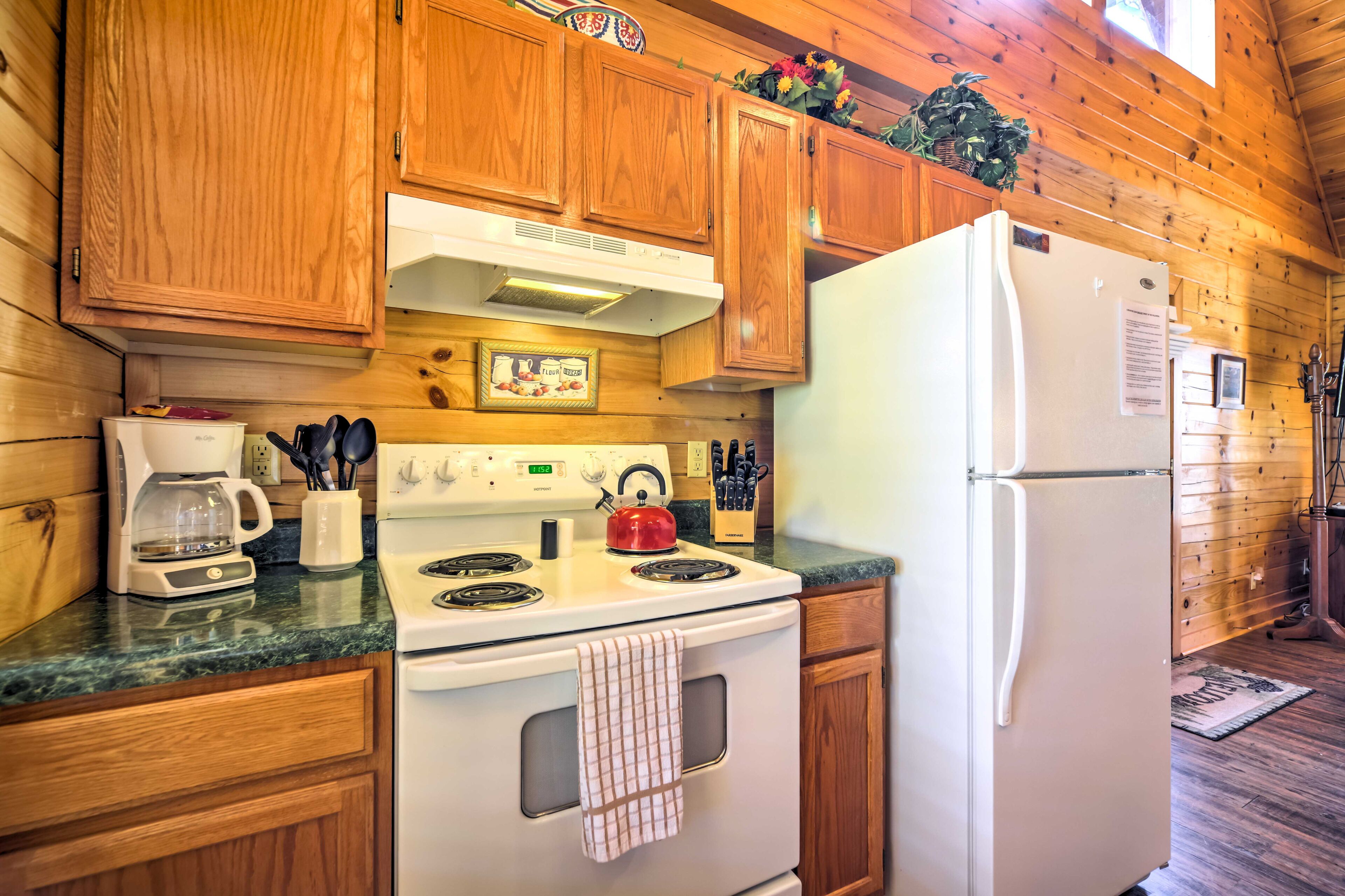 A kitchen with wooden cabinets, a white stove, a refrigerator, and a coffee maker.
