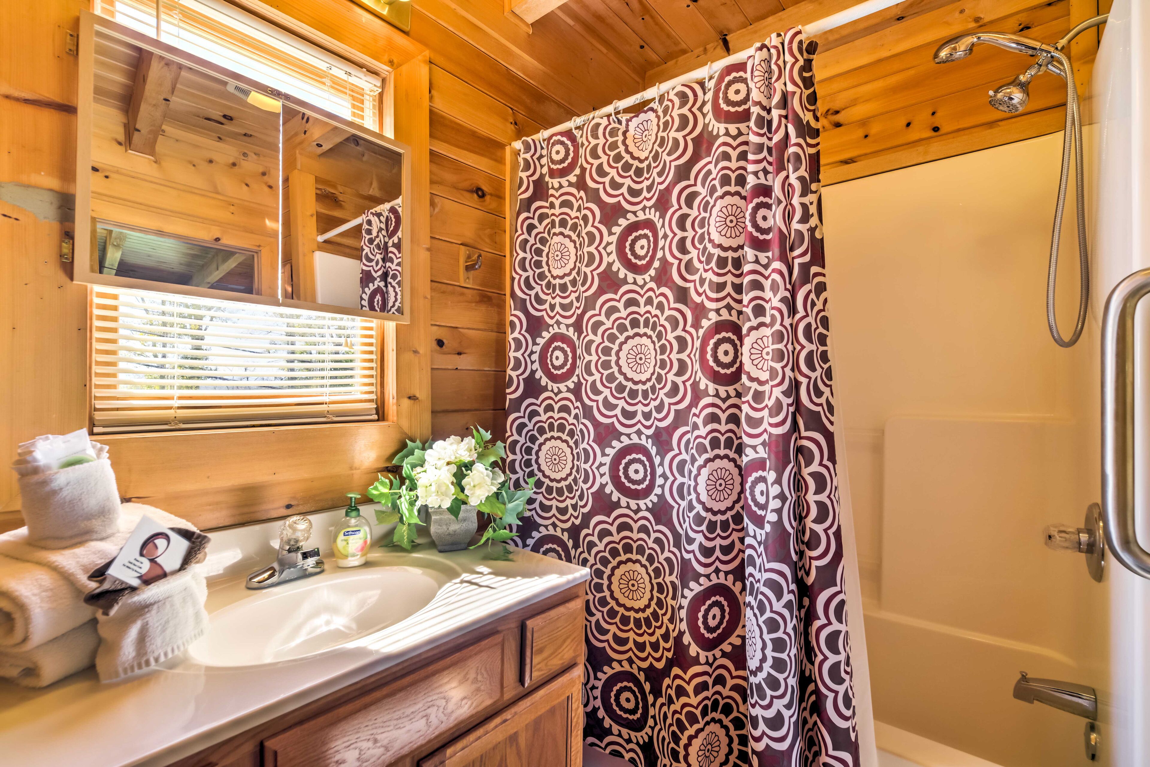 Baño de una cabaña de madera con lavabo, espejo y ducha.