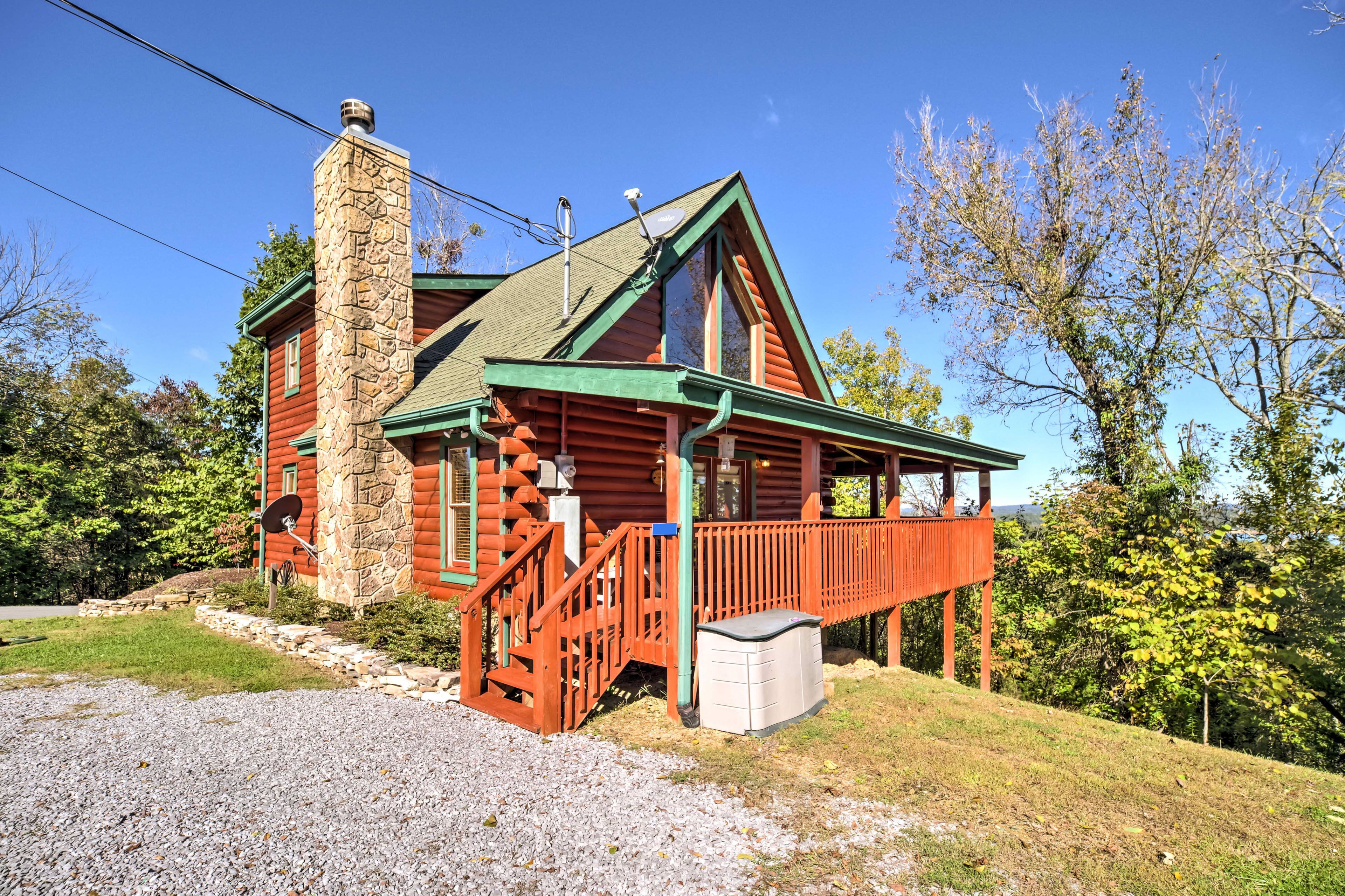 Une cabane en rondins avec une cheminée en pierre, une terrasse en bois et des fondations en pierre.