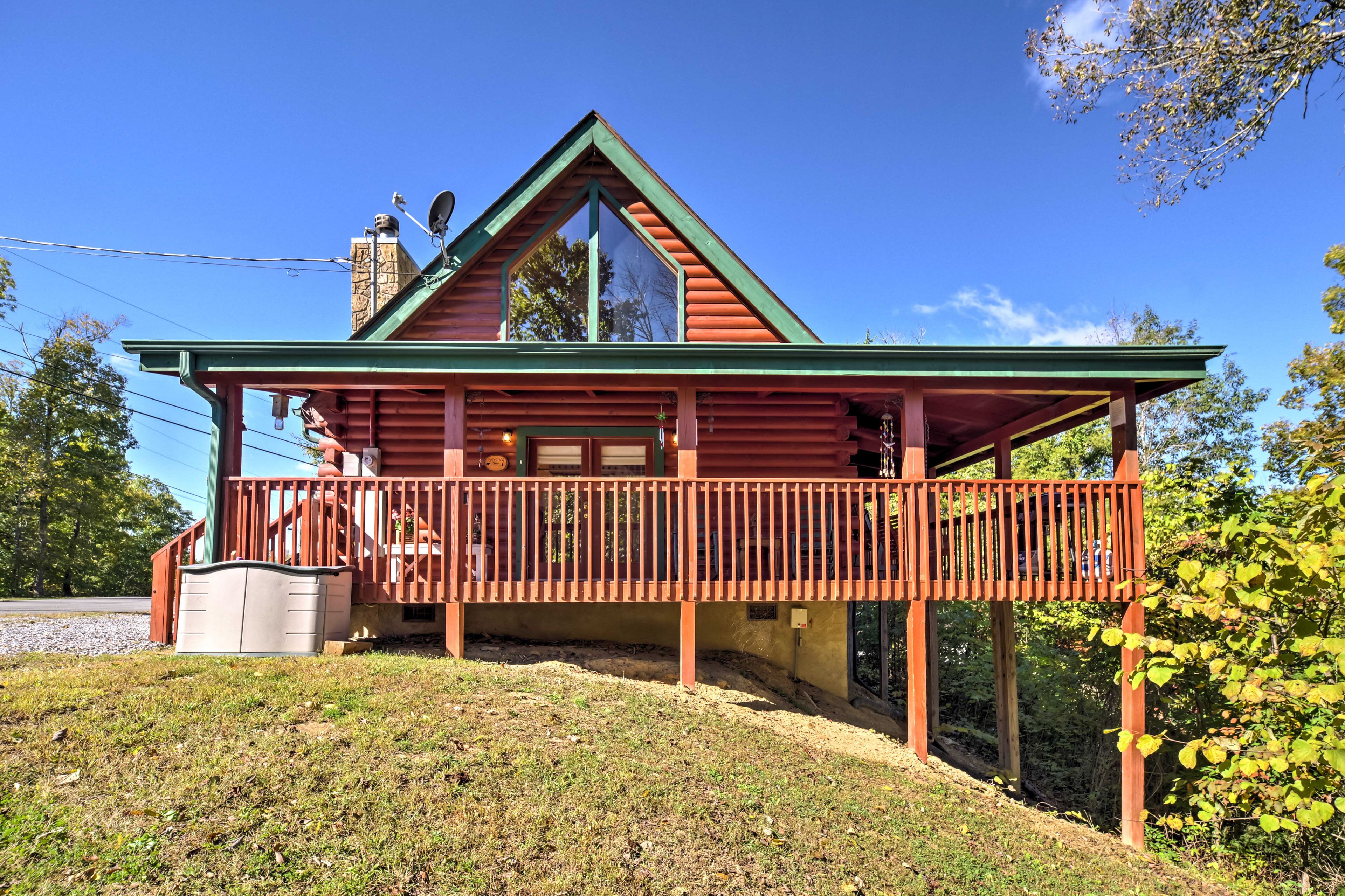 A log cabin with a green roof, a balcony, and a chimney.