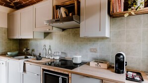 Eine Küche mit weißen Schränken, einem Backofen, einer Kaffeemaschine und einer Teeaufbewahrungsbox.