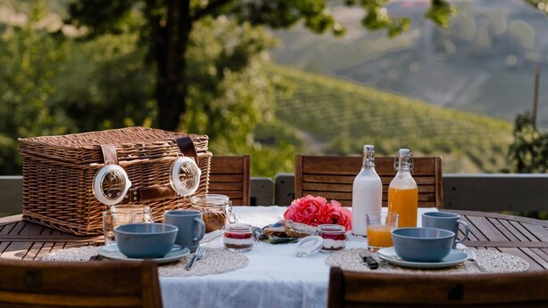 Ein Picknick mit einem Korb aus Weidengeflecht, Glasbehältern und einem Tisch mit weißer Tischdecke.