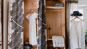 Ein Holzschrank mit mehreren Einlegeböden, einer Kleiderstange und einem gefalteten Kleidungsstück auf der obersten Ablagefläche.