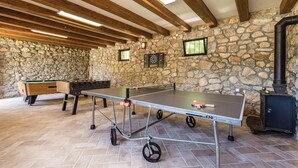 A ping pong table with wheels, a pool table, and a dartboard in a stone-walled room with wooden beams. - Pet friendly home in Perusic (Perusic)