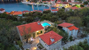 A coastal village with stone buildings, a marina, and a swimming pool.