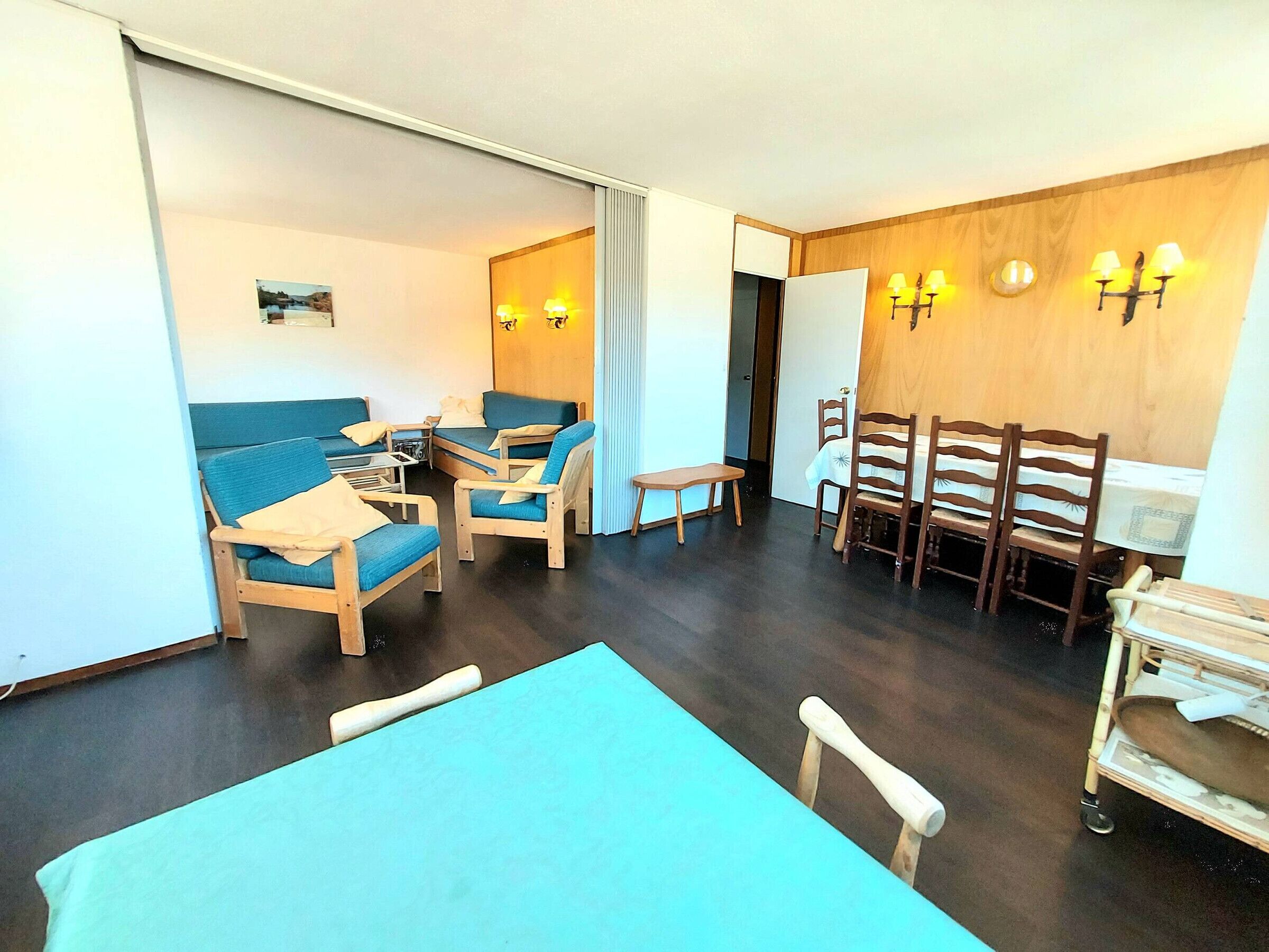 A room with a sofa set, a dining table with chairs, and a small table with a chair.