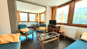 A room with two beds, a TV, a table, and a window with a view of trees. - Large apartment for 8 in Plagne Centre, balcony, pets allowed (La Plagne)