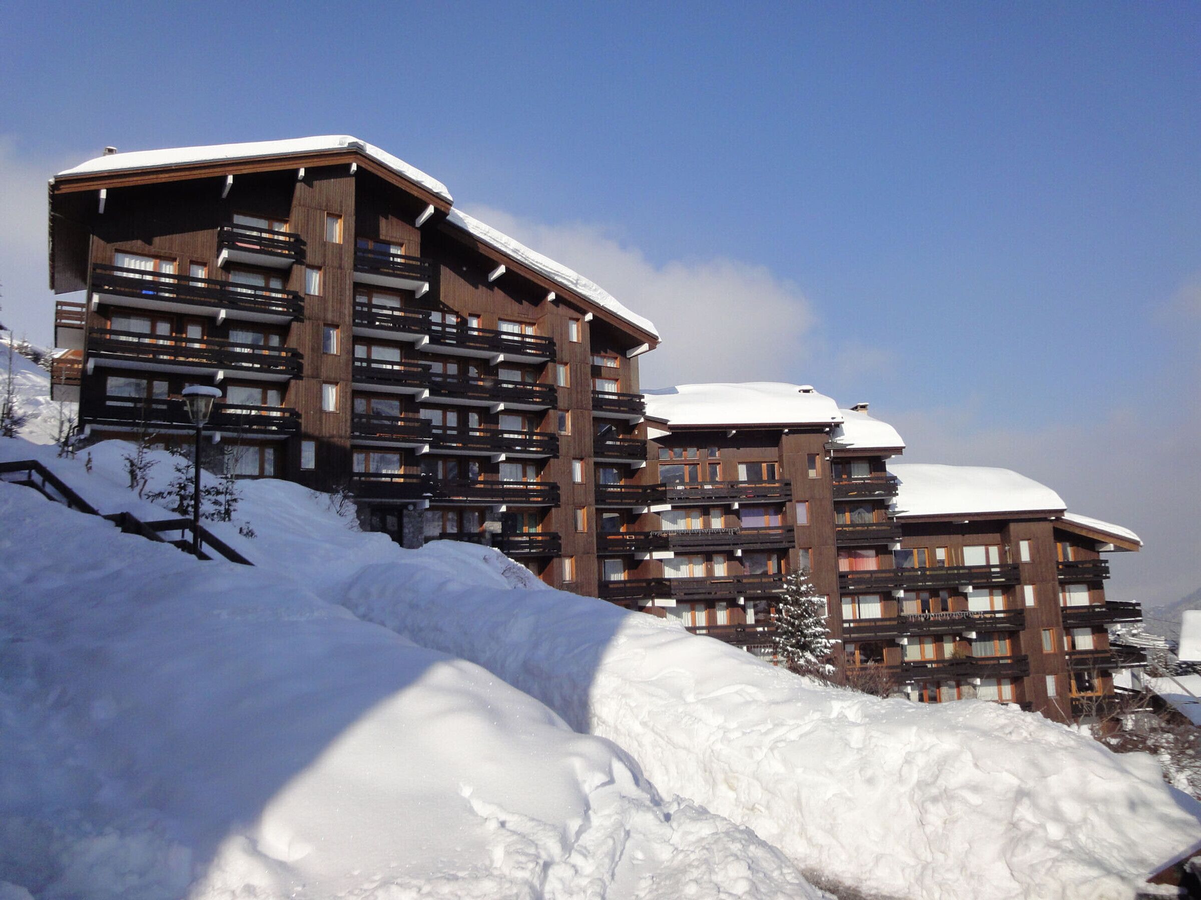 Een meerlaags hotel met balkons, sneeuw bedekte daken en een heldere lucht.