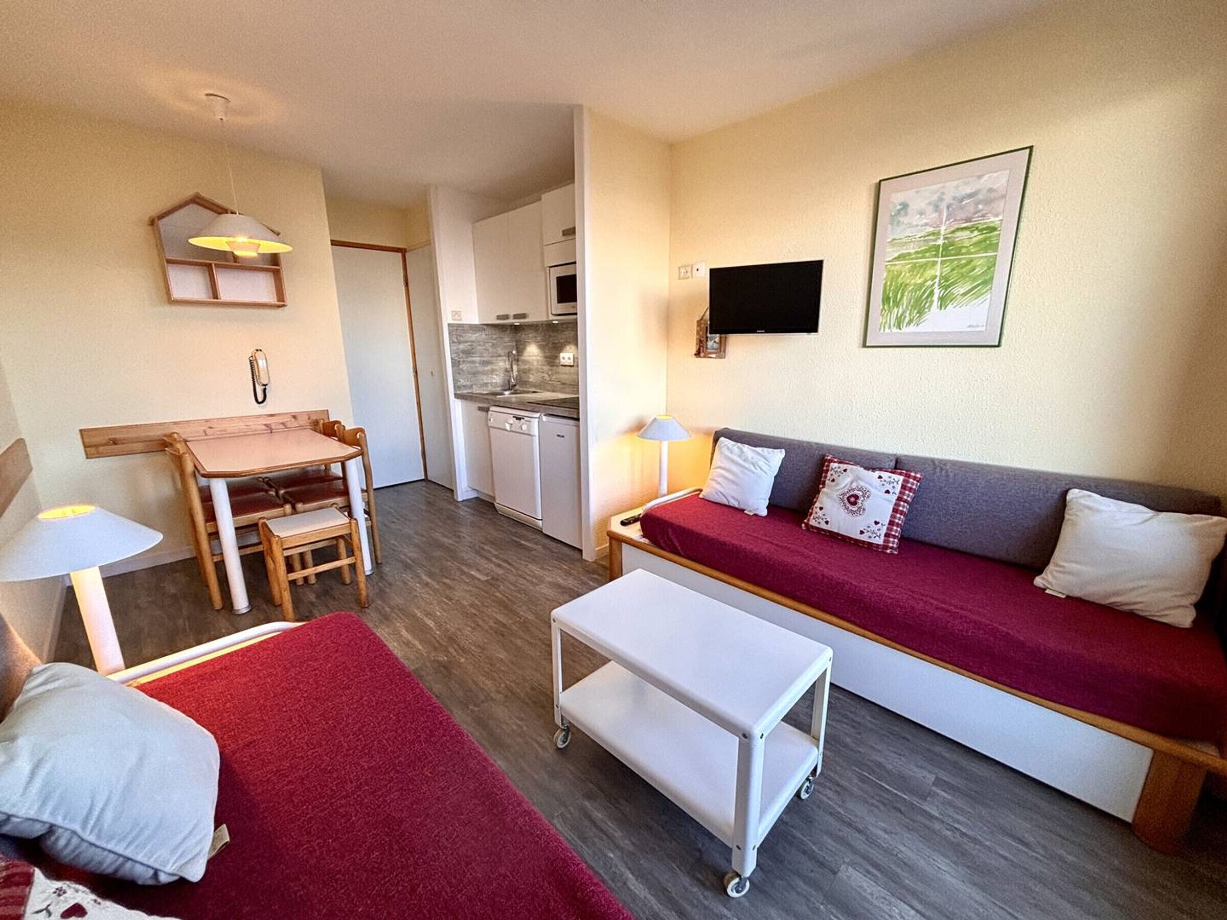 Een gezellige, compacte ruimte met een kitchenette, een bank, een eettafel en een klein karretje.