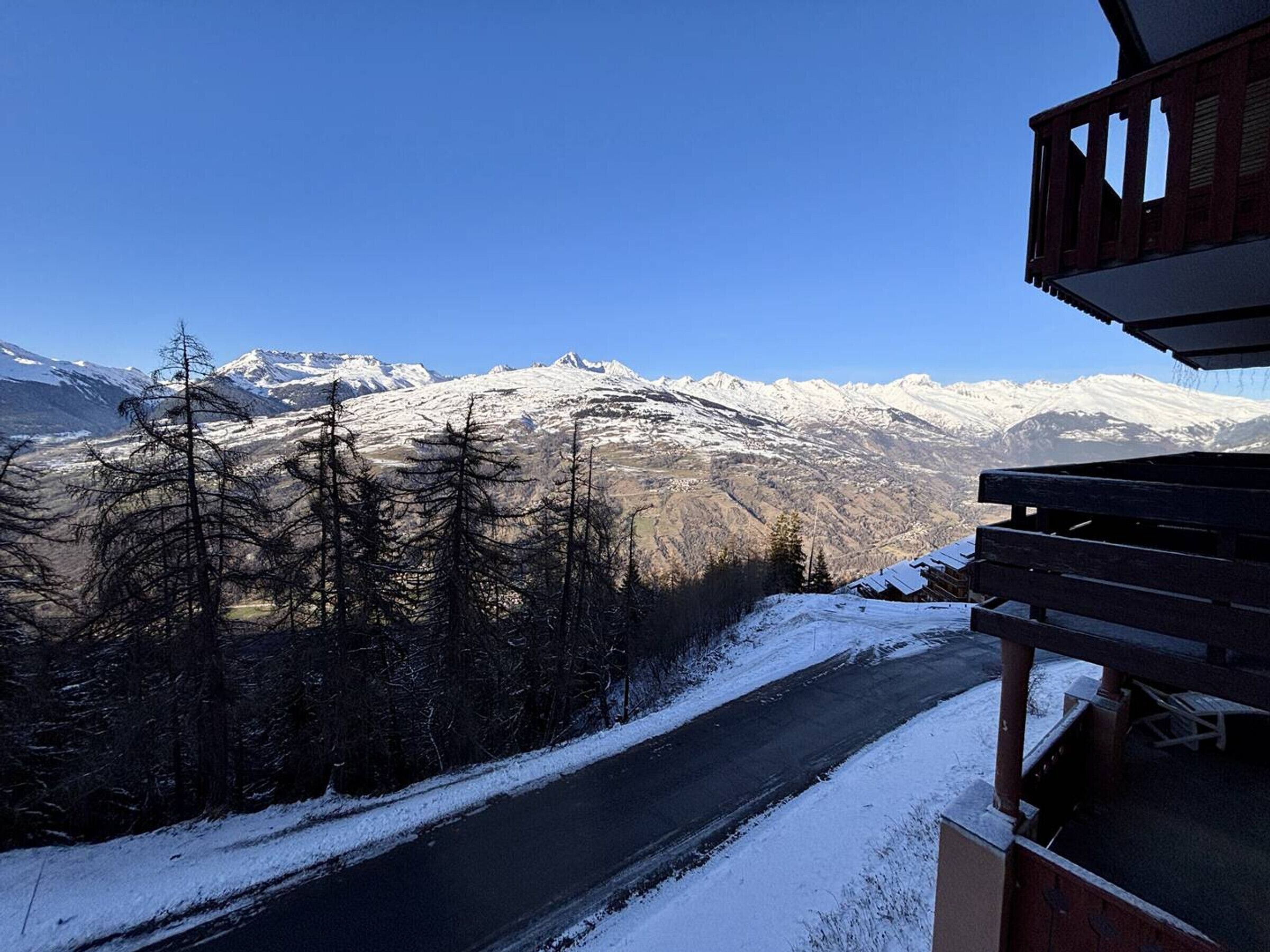 Gebirgslandschaft mit einer Straße, die zu einem Gebäude mit einem Holzbalkon führt.