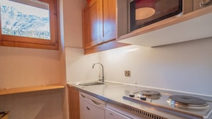 A compact kitchen with a sink, stove, and microwave.