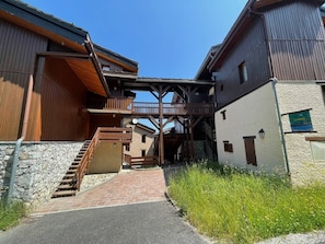 A building with a wooden exterior, a stone wall, and a brick pathway leading to a wooden staircase.