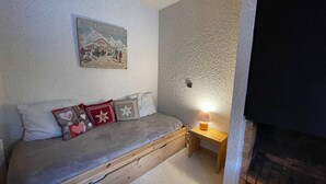 A cozy room with a bed, a small table, a wall-mounted picture, and a fireplace.