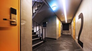 A hallway with a patterned floor, a staircase, and a door with a handle. - Sol Motel (Busan)