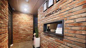 A reception area with a brick wall and a sign labeled "INFORMATION". - Sol Motel (Busan)