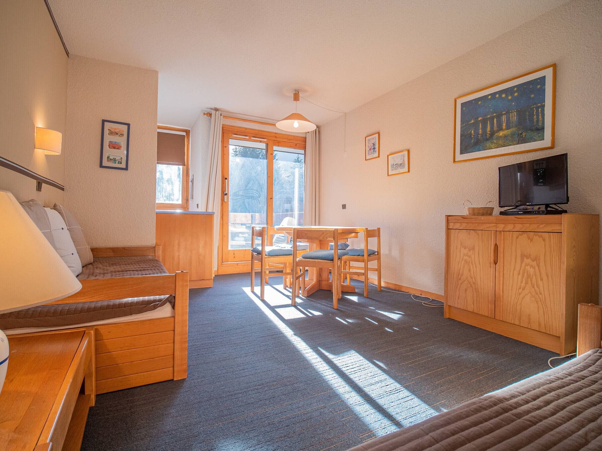 A cozy room with a bed, a desk, a chair, a television, and a window.