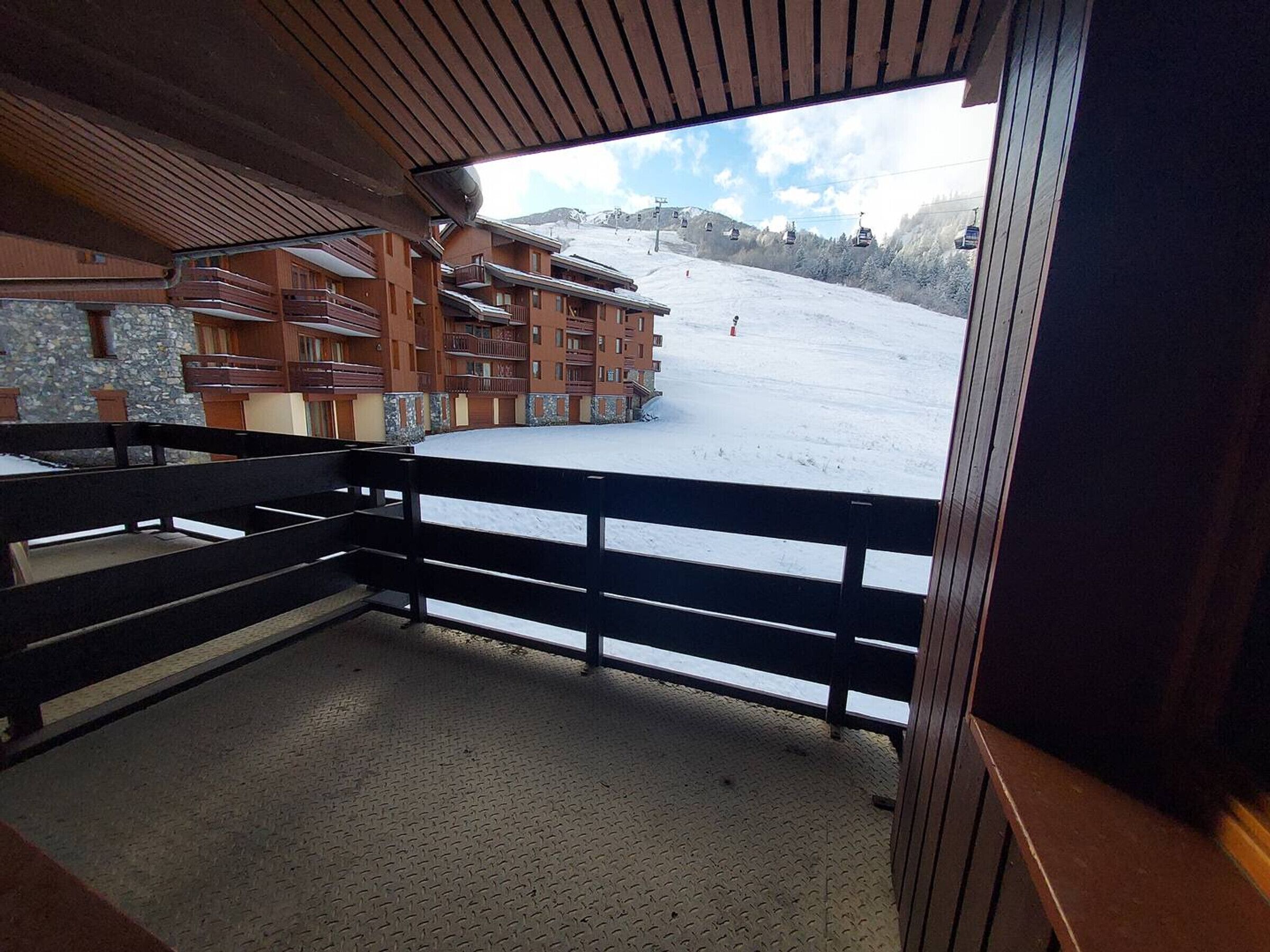 A snow-covered ski slope with a wooden building in the background.