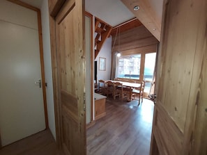 A wooden interior with a dining area, a large window, and a door.