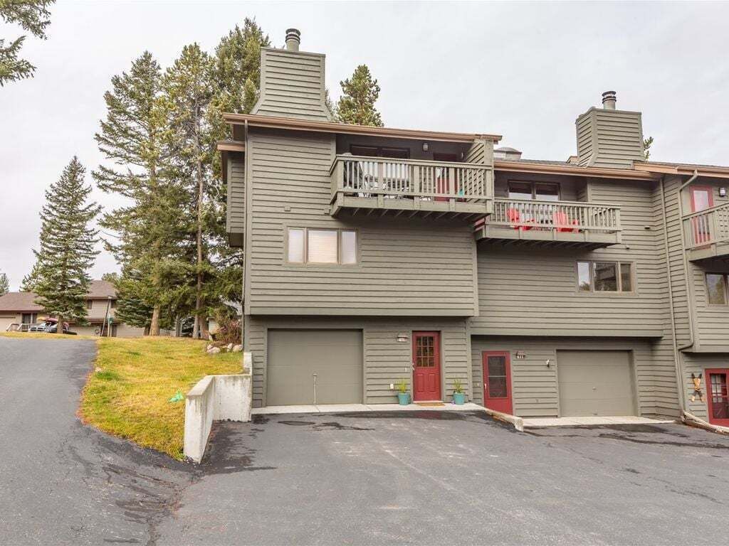 A two-story building with a red door, a balcony, and a garage.