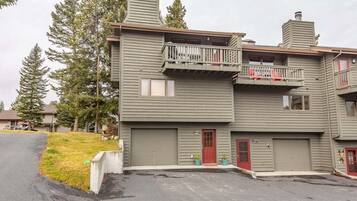 A two-story building with a red door, a balcony, and a garage.