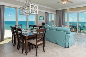 Enjoy ocean views from the large windows in this elegantly furnished room, featuring a dining table for six and a comfortable seating area with a sofa.