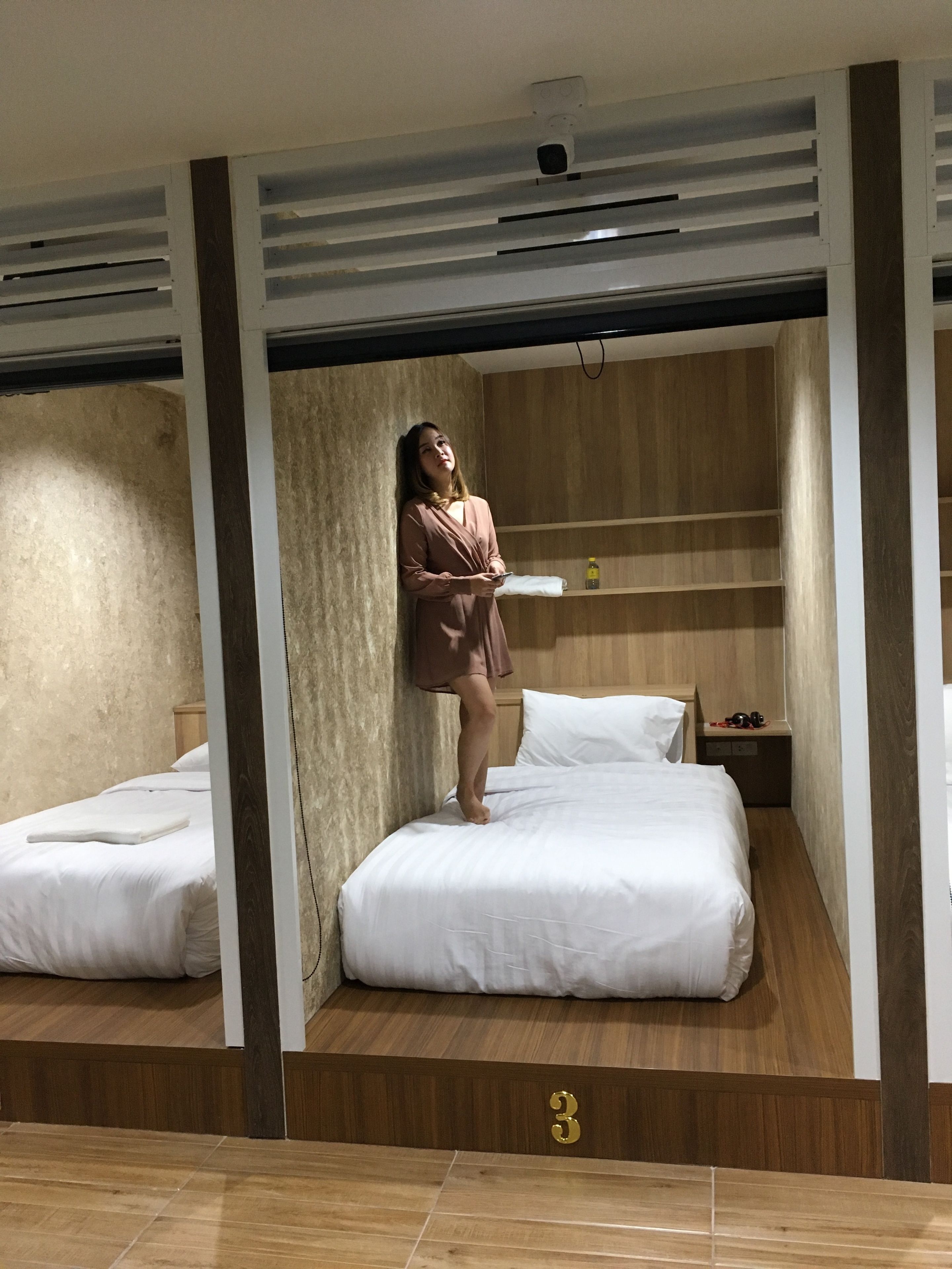A hotel room with two beds, a wooden floor, and a number '3' on the floor.