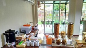 A breakfast bar with various food items, a coffee maker, and a view of the outdoor area.